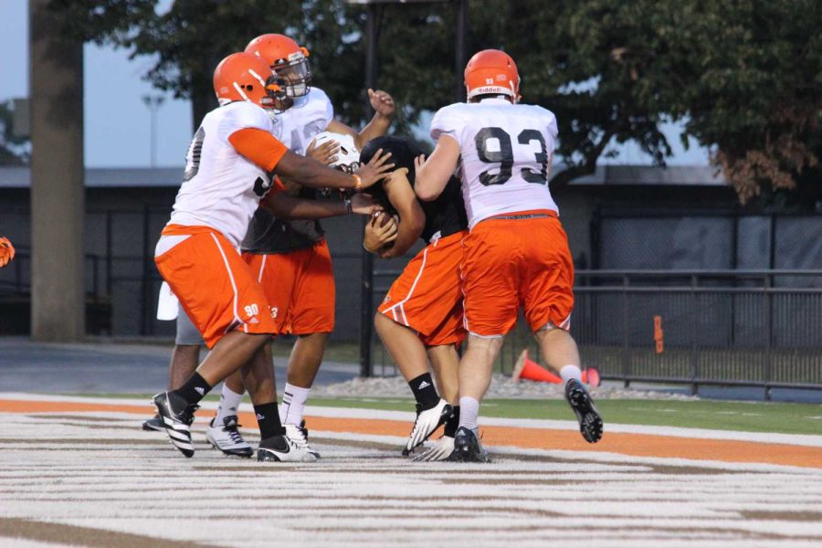 Ted Ouellet (93) pressures the quarterback with two defensive teammates during practice Wednesday night.
