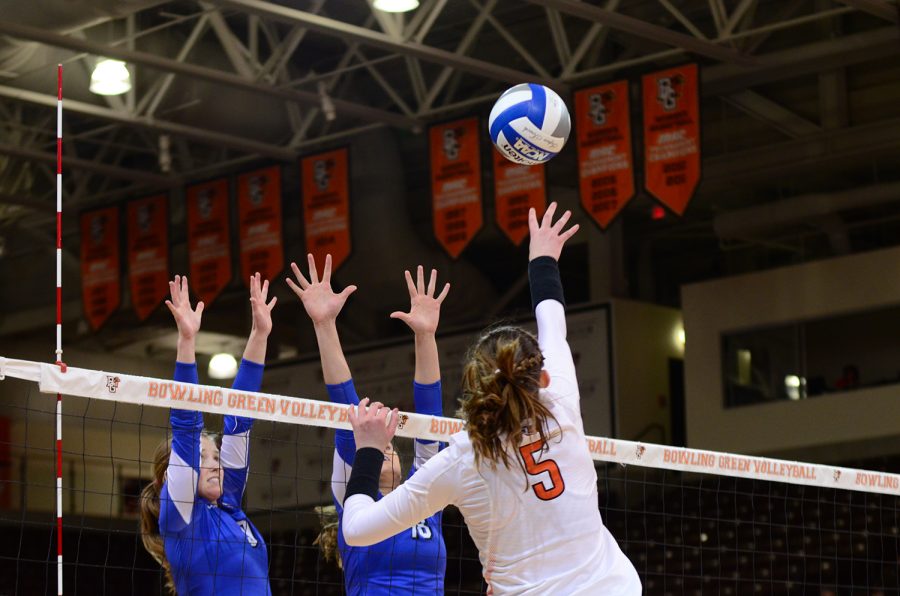 Outside hitter Jessi Holly goes for a spike over two Buffalo defenders.