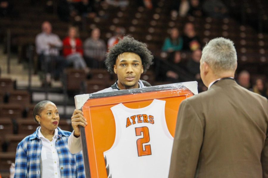 Ayers looking at camera while accepting his framed jersey
