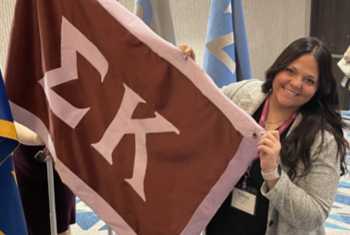 Picture of Tiffany Eckert holding the flag of her sorority, Sigma Kappa.