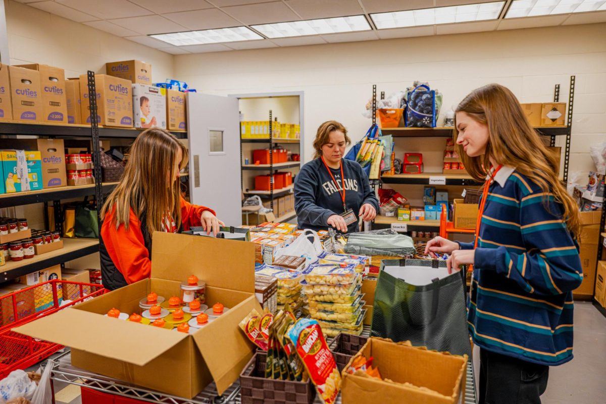 Photo of Grace Schneider, Cecilia Record and Paige Winkle filling the holiday boxes and bags at the Falcon Food Pantry.