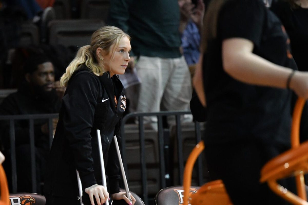 Lexi Fleming coming out of the locker room, watching her teammates while on crutches.
