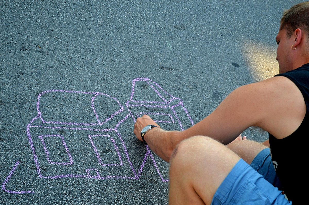 An event attendee takes advantage of free sidewalk chalk