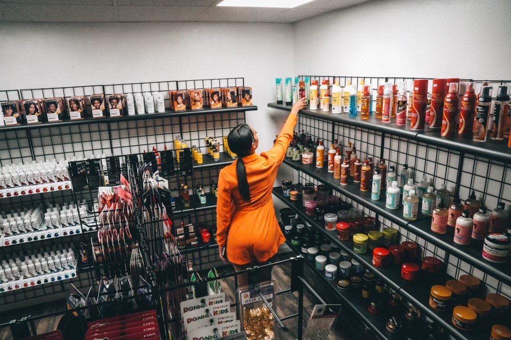 Below, the beauty supply store's owner, browses the shelves of her new store.