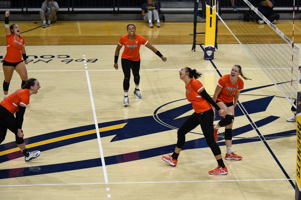 Toledo, OH - Falcons sophomore setter Jessica Andrews (11) and fifth year middle blocker Alexis Mettille (16) celebrating shutting down a Rockets attack at Savage Arena in Toledo, Ohio.