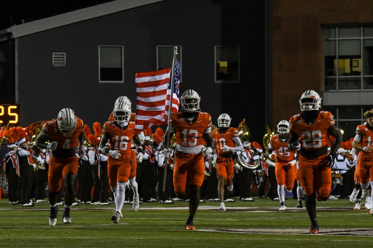 Bowling Green, OH - Falcons senior outside linebacker Charles Rosser (13) carrying out the American flag for the runout at Doyt L. Perry Stadium in Bowling Green, Ohio.