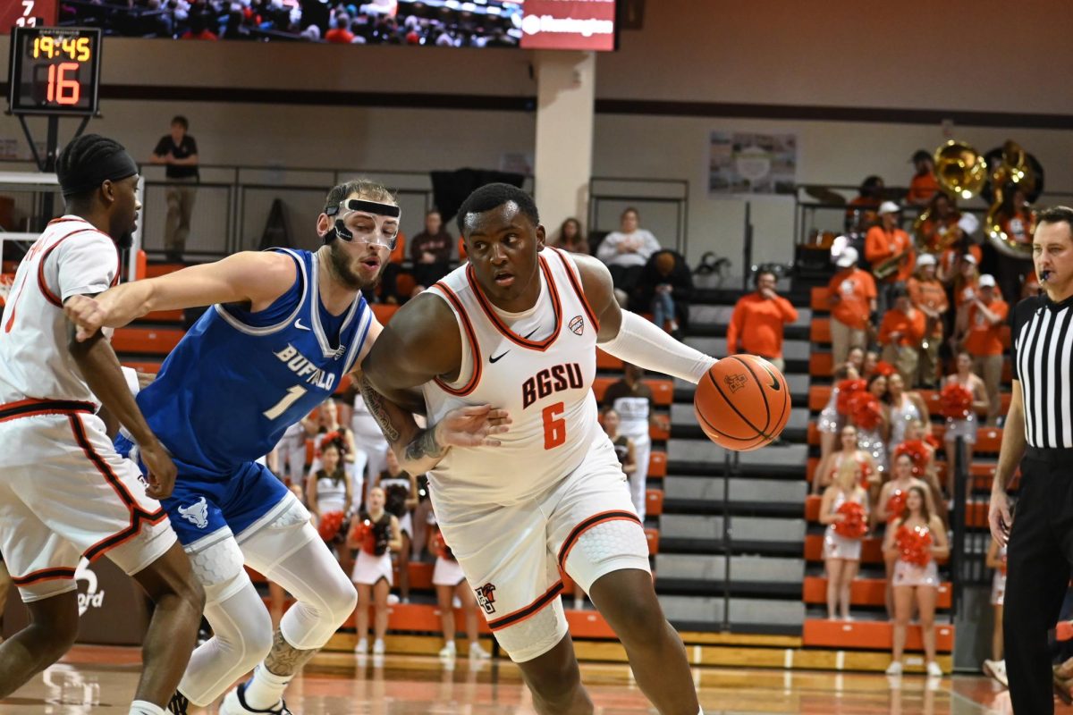 Bowling Green, OH - BGSU senior Marcus Johnson (6) dribbles past Buffalo player Noah Batchelor (1) to the basket in Bowling Green, Ohio.