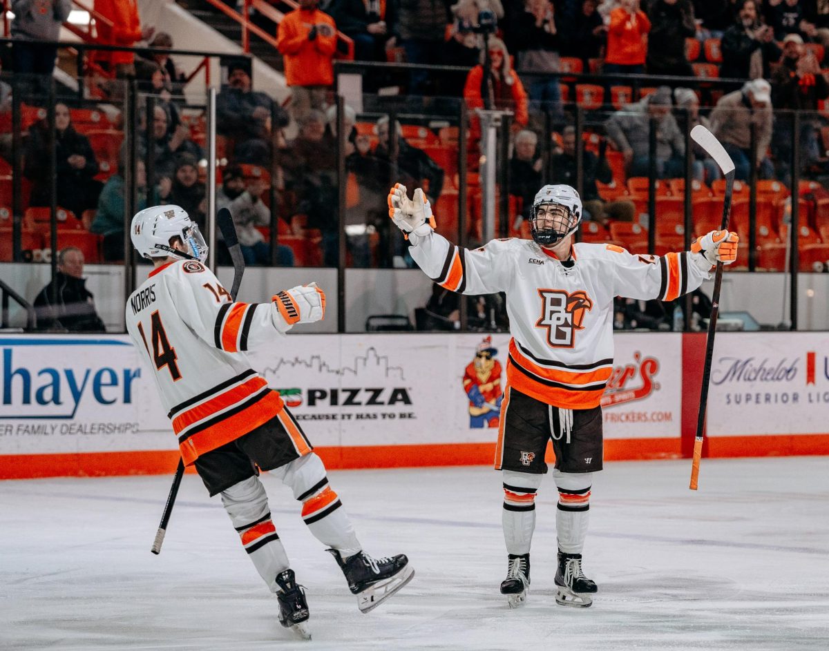 Bowling Green, OH – Falcons junior forward Brett Pfoh (13) celebrates with teammate Dalton Norris (14) after scoring a goal in the second period at Slater Family Ice Arena in Bowling Green, Ohio.