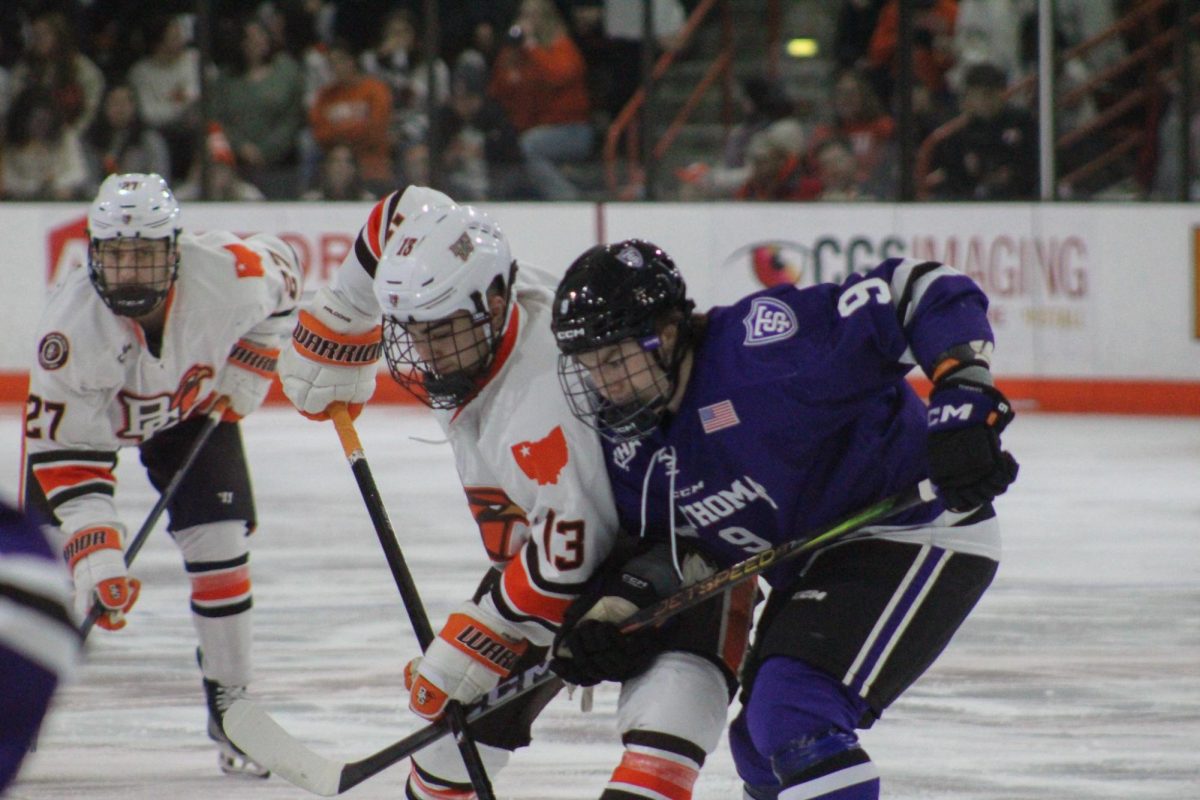 Bowling Green, OH - Falcons junior forward Brett Pfoh (13) fighting for the puck at Slater Family Ice Arena in Bowling Green, Ohio