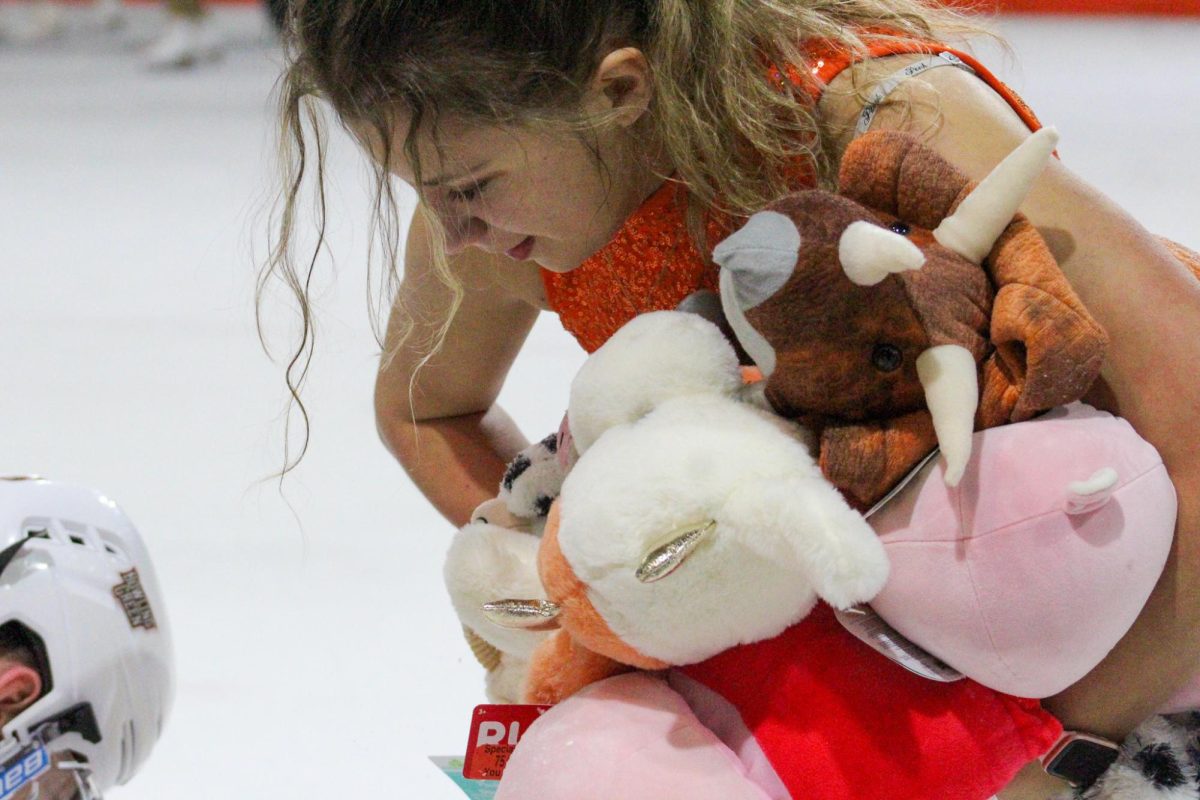 Bowling Green, OH - Falcons Spirit Skaters help pick up some stuffed animals for the Teddy Bear Toss at Slater Family Ice Arena in Bowling Green, Ohio