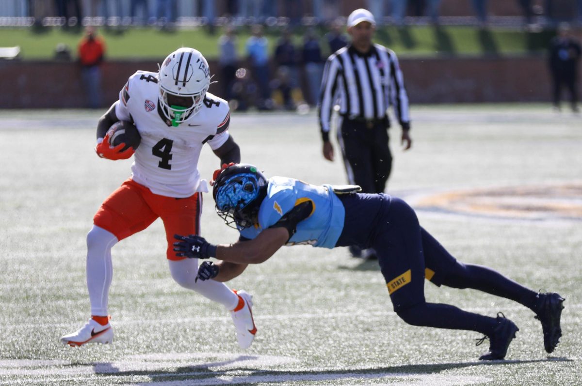 Kent, OH - Falcons junior running back Chris McMillian (4) stiff arms a defender while running down field at Dix Stadium in Kent, Ohio.