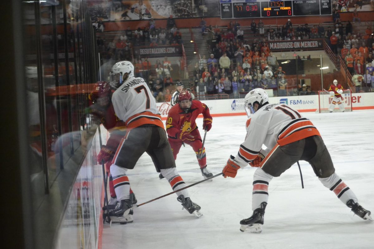 Bowling Green, OH - Falcons junior defenseman Rihards Simanovičs (7) and freshman forward Noah Morneau (11) battling for the puck on the boards at the Slater Family Ice Arena in Bowling Green, Ohio.