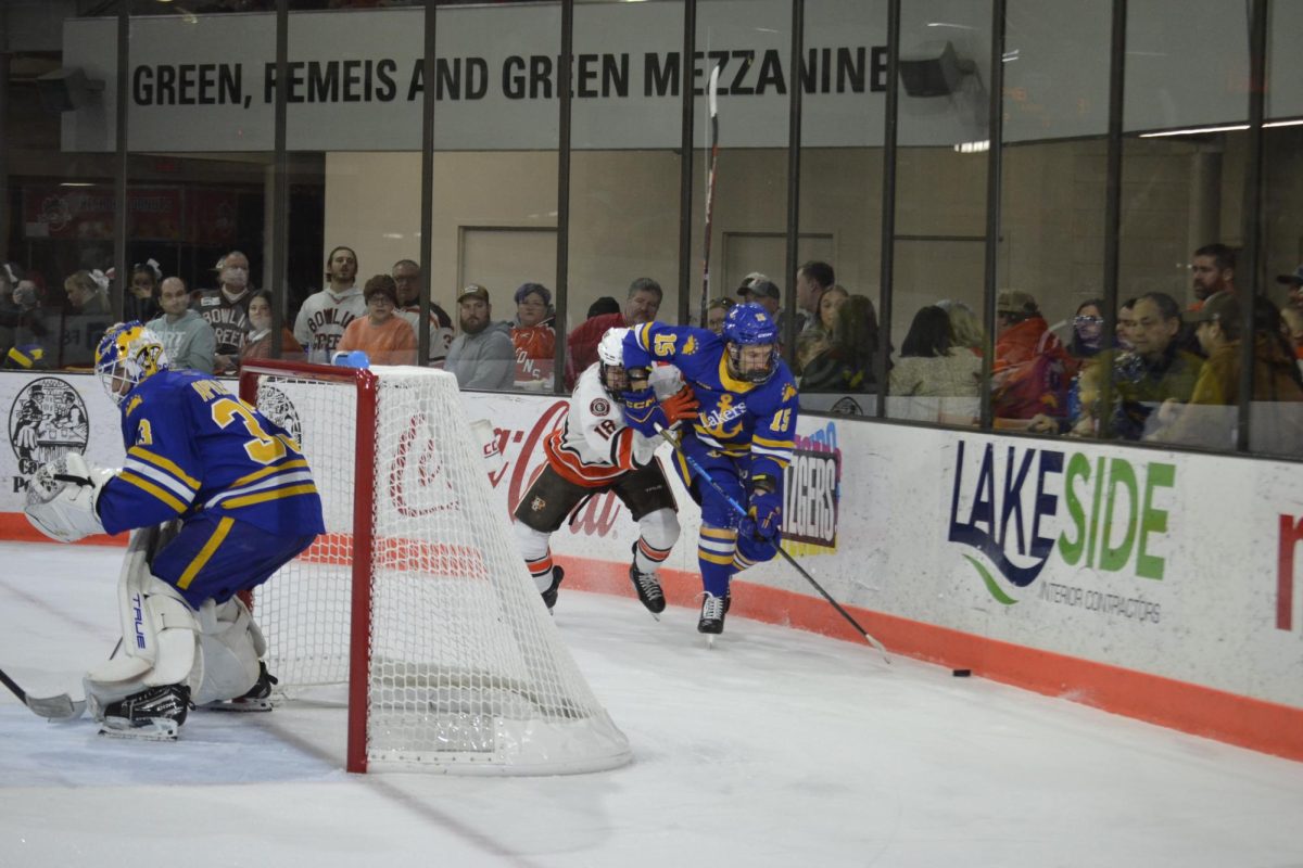 Bowling Green, OH - Falcons senior forward Quinn Emerson (18) fights a Laker for the puck at Slater Family Ice Arena in Bowling Green, Ohio.