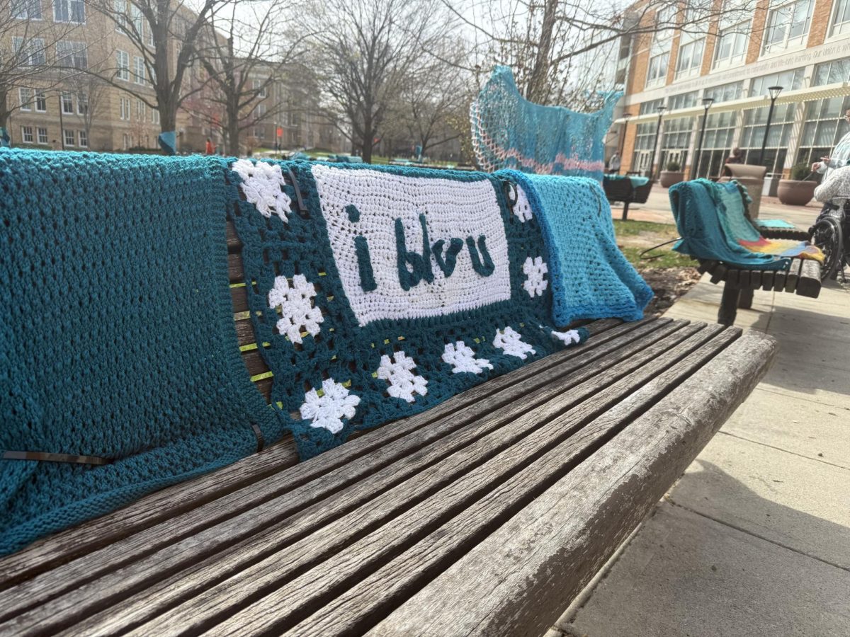 A bench covered in teal crochet to bring awareness to sexual violence