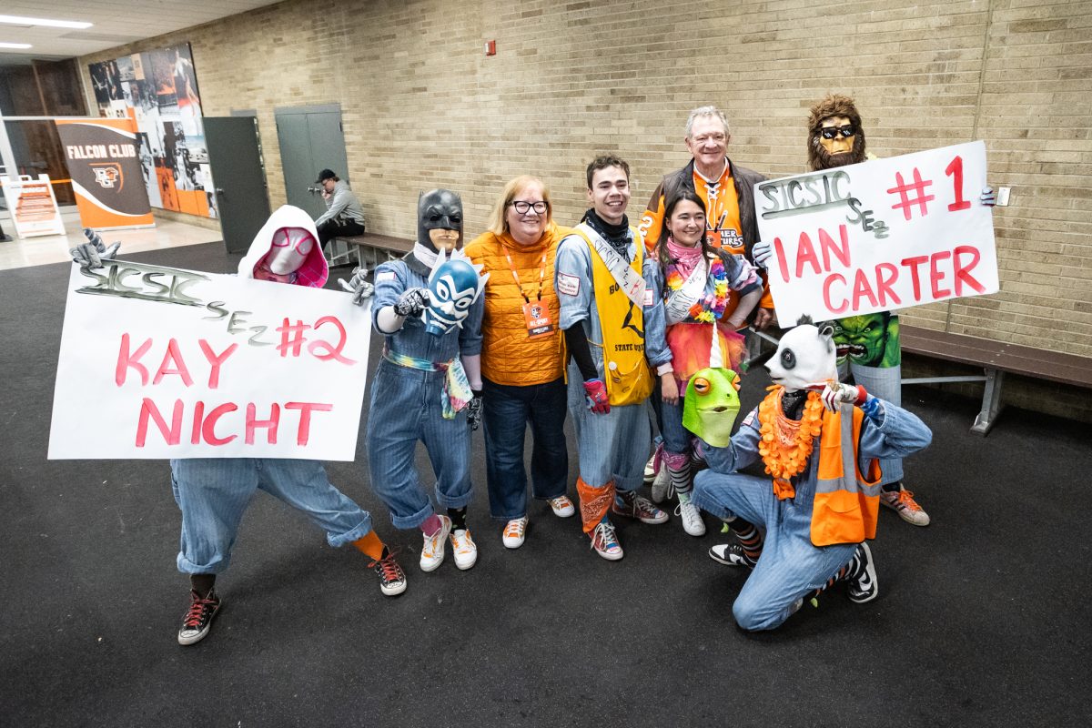 Bowling Green, OH - Members of SICSIC gather for a picture with President Rogers and his wife after revealing the identities of Geico (Kay Nicht) and Blue Spirit (Ian Carter) during a game between the Minnesota State Mavericks and the Bowling Green Falcons at the Slater Family Ice Arena in Bowling Green, Ohio.