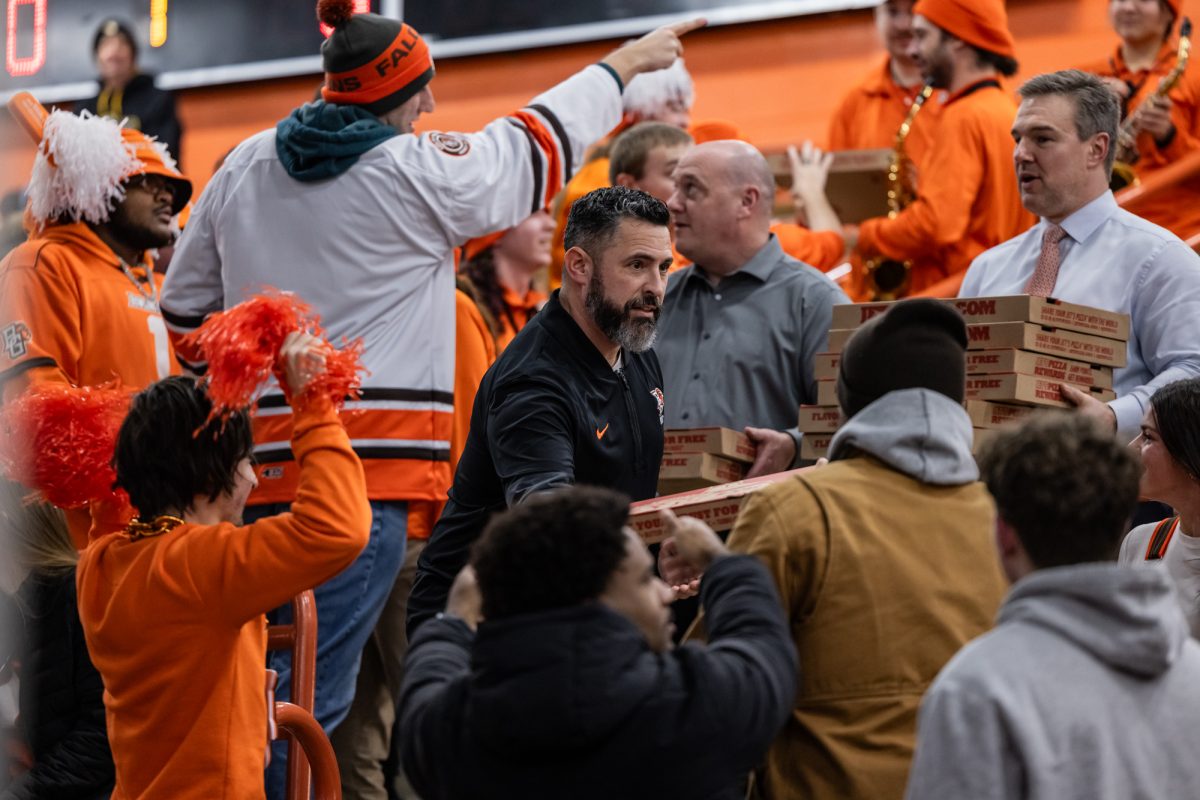 Bowling Green, OH - Bowling Green head coach Dennis Williams hands out Jet’s Pizza to the Bleacher Creatures before a game between the Notre Dame Fighting Irish and the Bowling Green Falcons at the Slater Family Ice Arena.