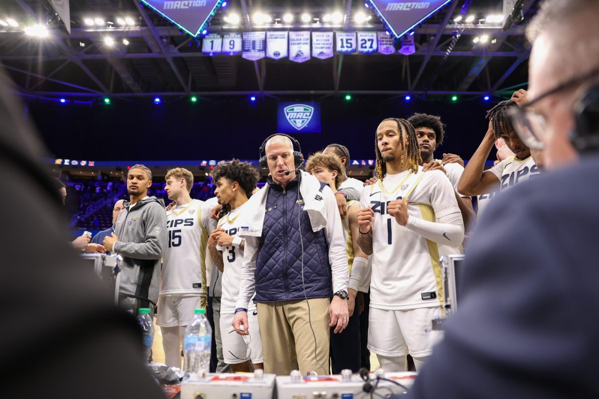 Cleveland, OH - Akron Zips head coach John Groce is flanked by members of his team as he speaks on TV following a close victory over the Buffalo Bulls in the quarterfinal round of the men's MAC Basketball Tournament at Rocket Arena in Cleveland, Ohio.