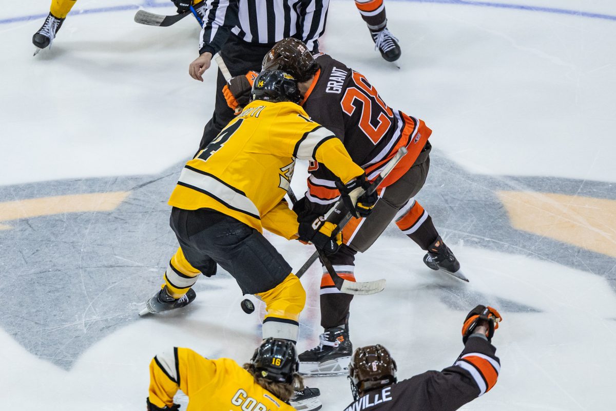 Houghton, MI - Huskies junior forward Max Koskipirtti (14) and Falcons senior forward Jaden Grant (28) go for the opening face-off during a game between the Bowling Green Falcons and the Michigan Tech Huskies at the John MacInnes Student Ice Arena, in Houghton, Michigan.
