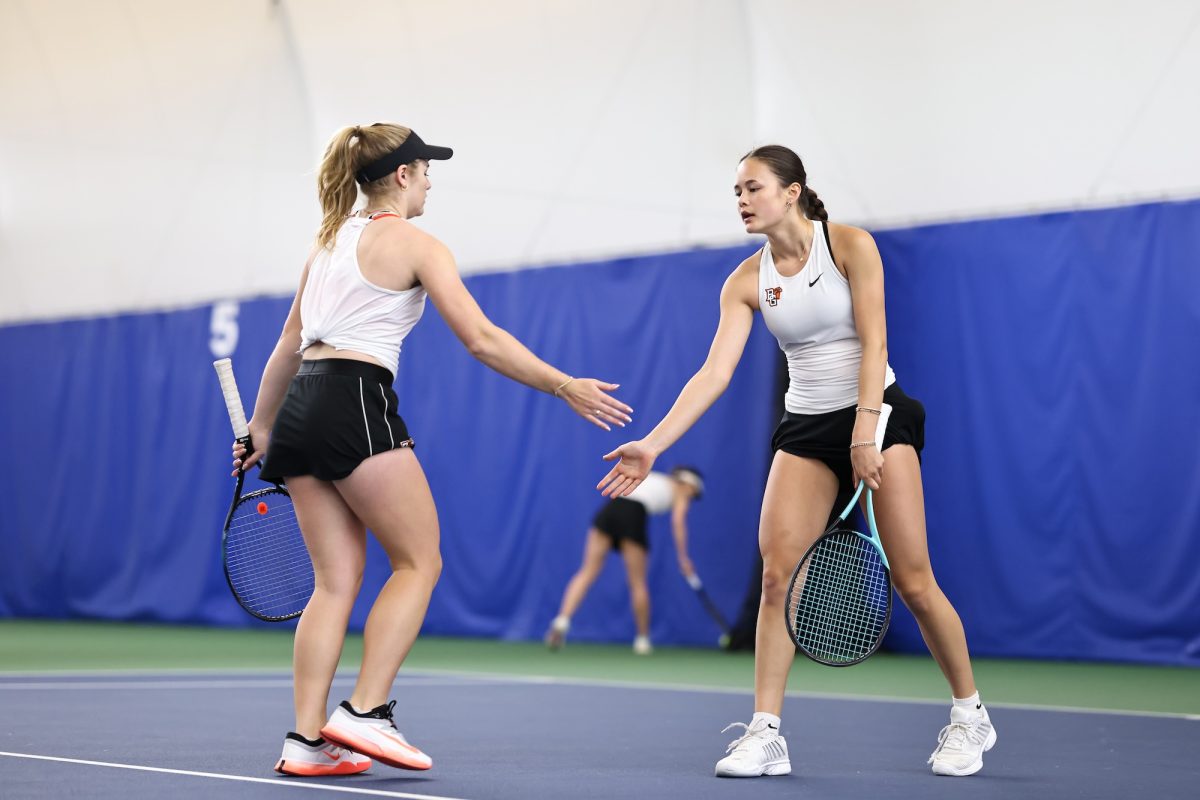 Perrysburg, OH - Falcons junior Libby Blair (left) high-fives freshman Kiera Taylor (right) during doubles play at the Perrysburg Tennis Center in Perrysburg, Ohio.